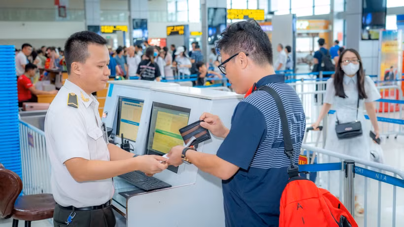 Nhân viên an ninh hàng không kiểm tra giấy tờ hành khách làm thủ tục lên máy bay. (Ảnh: PV/Vietnam+)