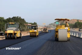 Nhà thầu huy động máy móc, nhân lực để thảm những mét bê tông nhựa cuối cùng để thi công tiếp hệ thống an toàn giao thông. (Ảnh: Khánh Hùng/Vietnam+)