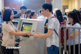 Nhân viên an ninh hàng không kiểm tra giấy tờ hành khách làm thủ tục đi máy bay tại Cảng Hàng không quốc tế Nội Bài. (Ảnh: PV/Vietnam+)