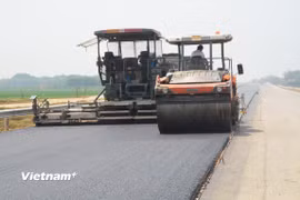 Nhà thầu thi công thảm bê tông nhựa một dự án đường bộ. (Ảnh: Việt Hùng/Vietnam+)