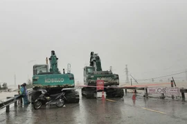 Lực lượng chức năng cấm đường và có các biển cảnh báo phương tiện không được lưu thông qua đoạn đường bị ngập, sạt lở. (Ảnh: PV/Vietnam+)