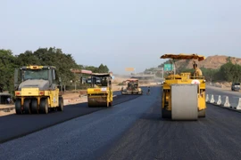 Nhà thầu huy động máy móc, nhân lực để thảm những mét bê tông nhựa trên đoạn tuyến cao tốc. (Ảnh: Việt Hùng/Vietnam+)