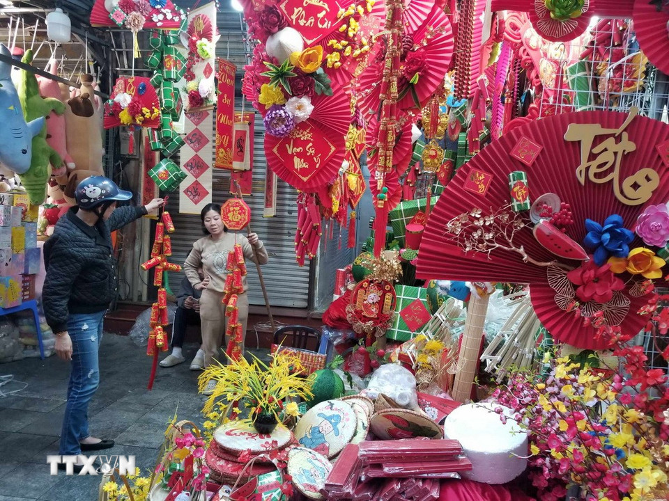Một người mua tham khảo giá và các sản phẩm trang trí Tết. (Nguồn: Thái Hà/Vietnam+)