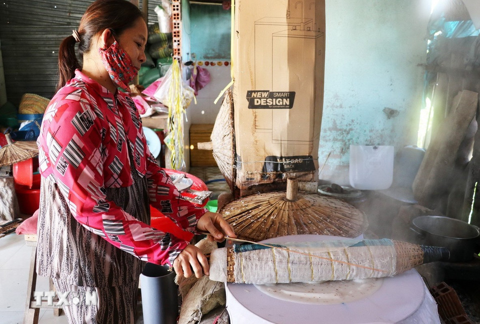 Công đoạn lấy bánh vừa hấp chín ra đòi hỏi sự khéo léo để tránh bánh bị giòn, dễ vỡ. (Ảnh: Hữu Chí/TTXVN)