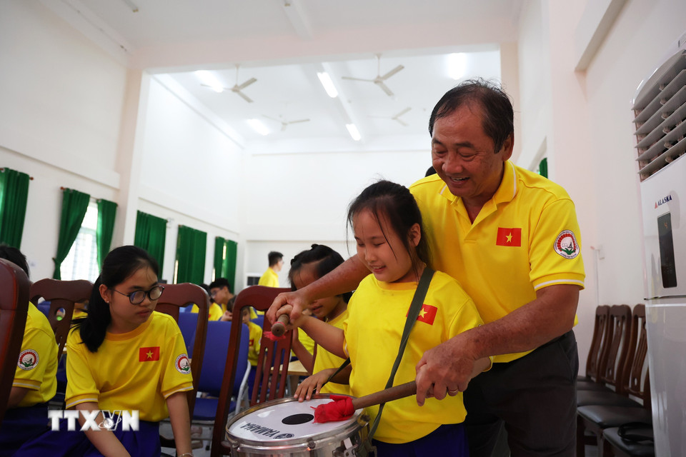 Thầy Nguyễn Phi Hùng, giáo viên định hướng và di chuyển Trường Phổ thông đặc biệt Nguyễn Đình Chiểu, hướng dẫn các em nhỏ khiếm thị đánh trống cổ vũ cho U22 Việt Nam trong trận chung kết Sea Games 33. (Ảnh: Hồng Đạt/TTXVN)