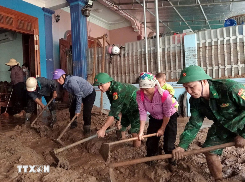 Cán bộ, chiến sỹ Đồn biên phòng Nậm Cắn giúp người dân xã Mường Xén (Nghệ An) dọn dẹp, khắc phục hậu quả sau lũ. (Ảnh: TTXVN phát)