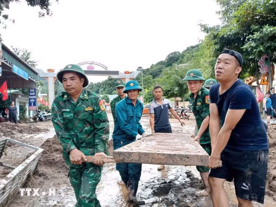 Cán bộ, chiến sỹ Đồn biên phòng Nậm Cắn giúp người dân xã Mường Xén (Nghệ An) dọn dẹp, khắc phục hậu quả sau lũ. (Ảnh: TTXVN phát)