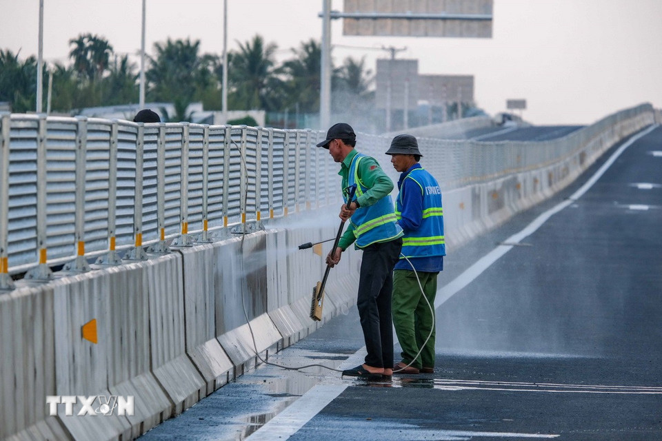 Công nhân vệ sinh, làm sạch dải phân cách và lan can trước thời điểm thông xe. (Ảnh: Thanh Liêm/TTXVN)