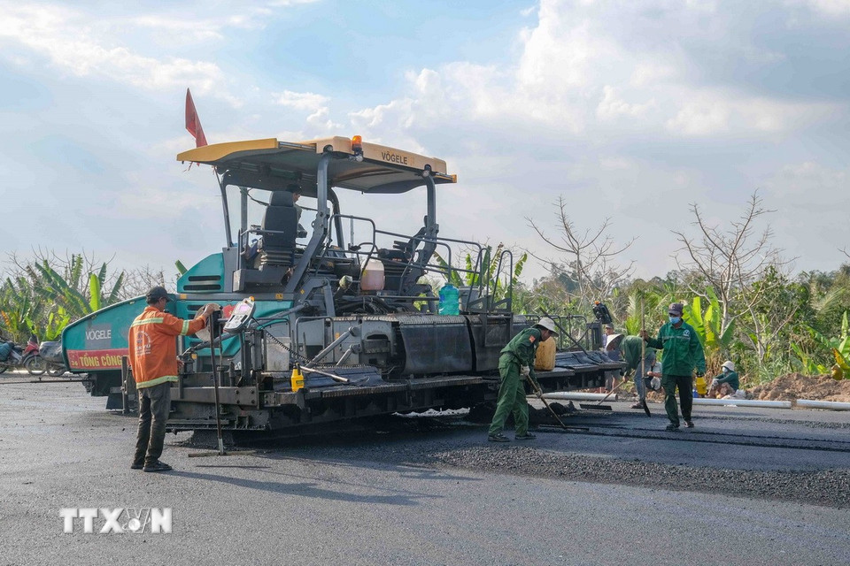 Thiết bị chuyên dụng và nhân công tập trung thi công thảm nhựa mặt đường đoạn gần nút giao IC2. (Ảnh: Thanh Liêm/TTXVN)