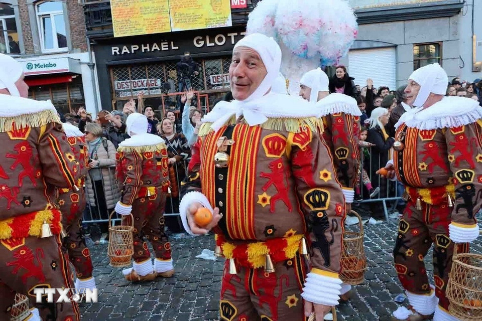 Trong những bộ đồ đỏ, vàng và đen, mũ lông đà điểu, guốc gỗ, các Gilles diễu hành khắp thành phố và mang những giỏ đựng cam để ném cam cho đám đông với ý nghĩa mang lại may mắn. (Ảnh: Hương Giang/TTXVN)