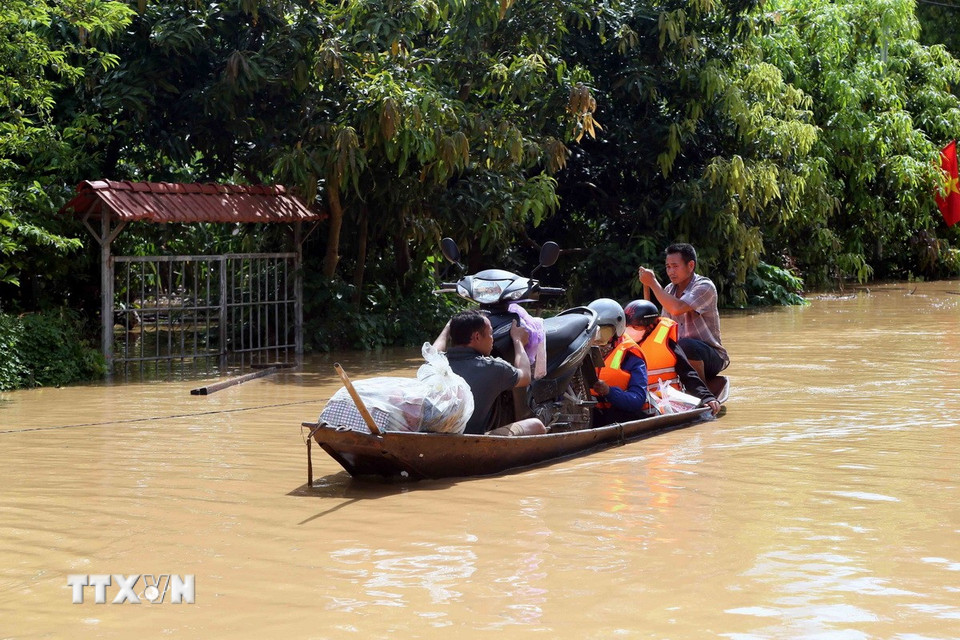 Hỗ trợ người dân ra khỏi vùng ngập lụt tại xã Mường Hung. (Ảnh: Quang Quyết/TTXVN)