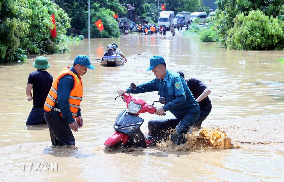 Hỗ trợ người dân ra khỏi vùng ngập lụt tại xã Mường Hung. (Ảnh: Quang Quyết/TTXVN)