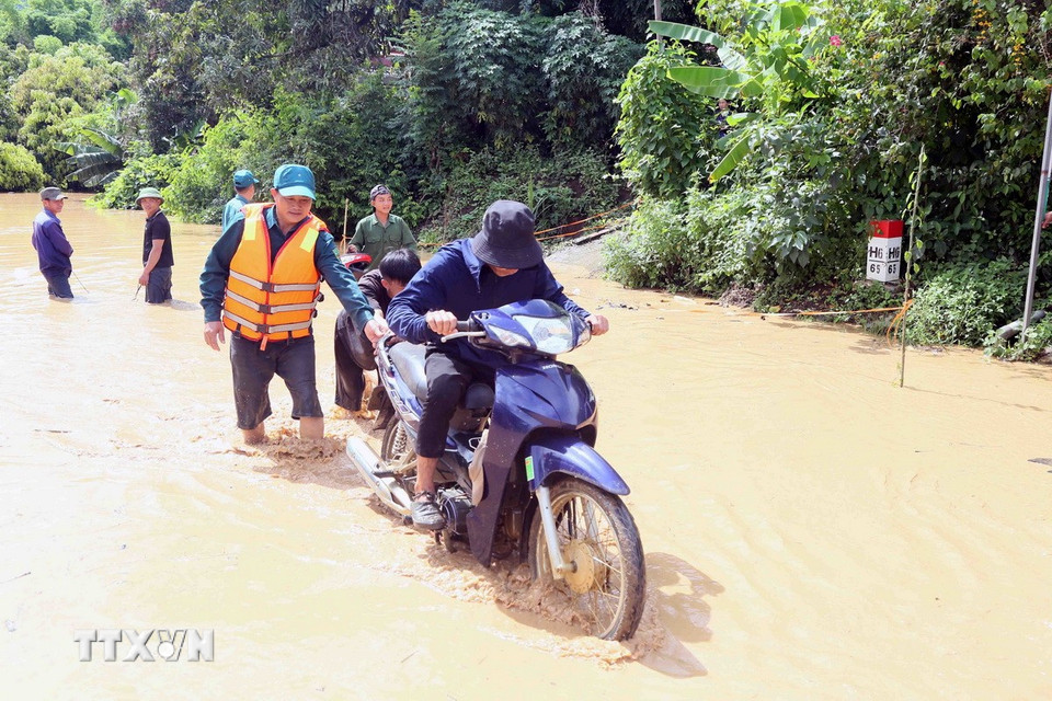 Hỗ trợ người dân ra khỏi vùng ngập lụt tại xã Mường Hung. (Ảnh: Quang Quyết/TTXVN)