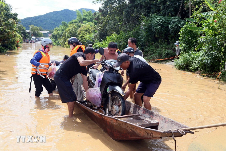 Hỗ trợ người dân ra khỏi vùng ngập lụt tại xã Mường Hung. (Ảnh: Quang Quyết/TTXVN)