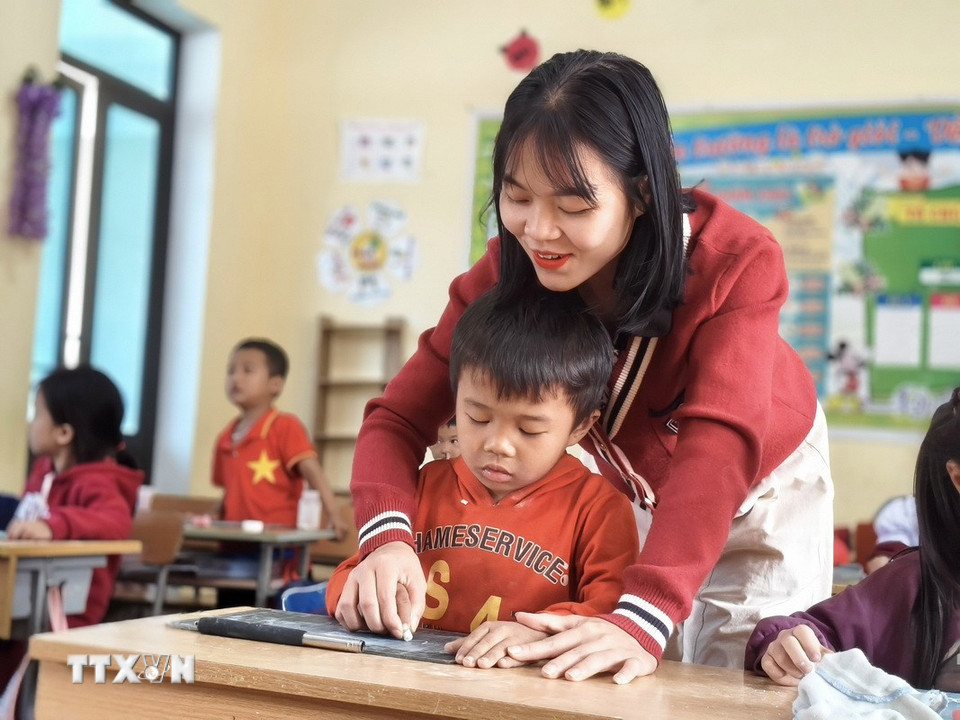 Cô giáo Đinh Thị Hải Anh hướng dẫn học sinh dân tộc Chứt viết chữ. (Ảnh: Hữu Quyết/TTXVN)