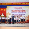 Các học sinh nghèo, hiếu học tại xã Long Chữ, tỉnh Tây Ninh nhận học bổng từ Phó Thủ tướng Chính phủ Lê Tiến Châu (phải) và Chủ tịch UBND tỉnh Tây Ninh Lê Văn Hẳn (trái). (Ảnh: Giang Phương/TTXVN)