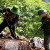 Đội quy tập hài cốt liệt sỹ dùng dụng cụ thô sơ cạy từng tảng đá, tìm kiếm hài cốt liệt sỹ. (Ảnh: TTXVN phát)
