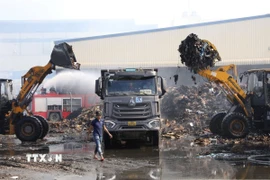 Các lực lượng dập tắt đám cháy thành công, tiến hành vận chuyển nguyên vật liệu và tàn tro ra ngoài khu vực tập kết. (Ảnh: Đức Phương/TTXVN)