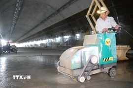 Công nhân thi công hạng mục tạo độ nhám cho mặt đường bên trong hầm. (Ảnh: Hữu Quyết/TTXVN)