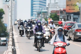 Khẩu trang, áo chống nắng là những thứ không thể thiếu của người dân khi tham gia giao thông. (Ảnh: Lê Đông/TTXVN)
