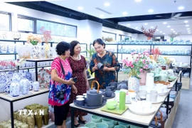 Giới thiệu sản phẩm gốm sứ với khách hàng tại Trung tâm Tinh hoa làng nghề Việt. (Ảnh: Phương Hoa/TTXVN)