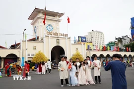 Người dân và khách tham quan chụp ảnh kỷ niệm tại Chợ Bến Thành. (Ảnh: Hồng Đạt/TTXVN)