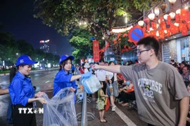 Lực lượng thanh niên tình nguyện hỗ trợ người dân dọn dẹp vệ sinh môi trường trên các tuyến phố. (Ảnh: Hoàng Hiếu/TTXVN)