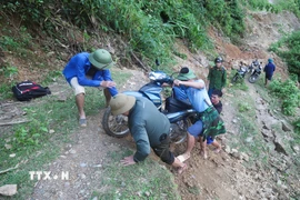 Lực lượng chức năng trong hành trình vượt qua các điểm mặt đường bị đứt gãy, sụt trượt xuống sâu hơn 2m để đến bản Na Ngân bị cô lập. (Ảnh: Xuân Tiến/TTXVN)