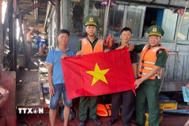 Hội viên Nghiệp đoàn nghề cá, tổ viên tổ đoàn kết trên biển thành phố Đà Nẵng nhận cờ Tổ quốc do Đồn biên phòng cửa khẩu cảng Kỳ Hà trao tặng. (Ảnh: Đoàn Hữu Trung/TTXVN)