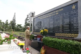 Cựu chiến binh thắp nén nhang cho đồng đội bên phần mộ tập thể liệt sỹ trong trận đánh Tết Mậu Thân tại Sân bay Biên Hòa năm 1968 tại Nghĩa trang Liệt sỹ tỉnh Đồng Nai. (Ảnh: Lê Xuân/TTXVN)