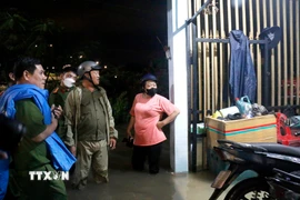 Lực lượng chức năng vận động người dân di chuyển khỏi vùng ngập sâu. (Ảnh: Nguyễn Thanh/TTXVN)