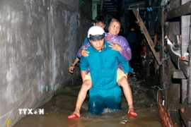 Hỗ trợ người già di chuyển khỏi khu vực ngập sâu đến nơi an toàn. (Ảnh: Nguyễn Thanh/TTXVN)
