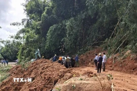 Lực lượng chức năng hỗ trợ phương tiện di chuyển qua điểm sạt lở sau khi đã cơ bản giải phóng hiện trường trong sáng 28/10. (Ảnh: TTXVN phát)