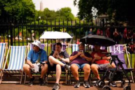 Người dân dùng ô che nắng ở London. (Ảnh: PA)