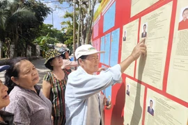 Giáo dân ấp Vĩnh Bắc, xã Vĩnh Thành (Vĩnh Long) tìm hiểu thông tin về các đại biểu ứng cử. (Ảnh: Huỳnh Phúc Hậu/TTXVN)