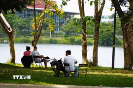 Người dân đến công viên bờ Bắc sông Hương, thành phố Huế để hóng mát, tránh nắng nóng gay gắt. (Ảnh: Nguyên Lý/TTXVN)