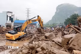 Hàng ngàn mét khối đất đá đổ tràn xuống Quốc lộ 32 đang được lực lượng chức năng nỗ lực xử lý. (Ảnh: Quý Trung/TTXVN)
