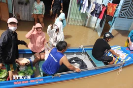 Các nhóm thiện nguyện dùng xuồng chèo đến phát cơm tận tay người dân vùng ngập nghiêm trọng. (Ảnh: Hồng Hiếu/TTXVN)