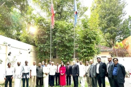 Các đại biểu chụp ảnh lưu niệm tại khuôn viên Đại sứ quán trong kỷ niệm 95 năm Ngày thành lập Đảng. (Ảnh: TTXVN phát)