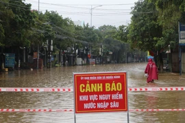 Nhiều tuyến đường tại xã Nghĩa Hành ngập sâu, chính quyền dựng rào chắn, căng dây cảnh báo cấm qua lại. (Ảnh: Đinh Hương/TTXVN)