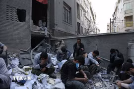 Người dân ngồi trên đống đổ nát của những tòa nhà bị phá hủy do xung đột tại Tehran, Iran ngày 15/3/2026. (Ảnh: THX/TTXVN)