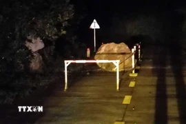 Tảng đá lớn lăn xuống từ vách núi, nằm chắn một phần mặt đường Hồ Chí Minh nhánh Tây. (Ảnh: TTXVN phát)