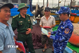 Cán bộ Vùng Cảnh sát biển 2 phối hợp với các lực lượng chức năng phổ biến các quy của pháp luật trong khai thác hải sản cho ngư dân. (Ảnh: Đoàn Hữu Trung/TTXVN)