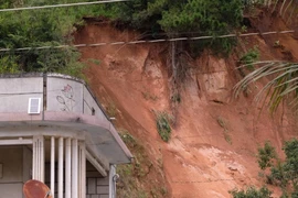 Một điểm sạt lở, sụt lún phía sau nhà dân ở thôn Lạc Thiện 2 vẫn tiếp tục lở đất vào trưa 24/11/2025. (Ảnh: Nguyễn Dũng/TTXVN)