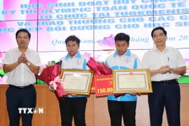 Bí thư Tỉnh ủy Quảng Nam Lương Nguyễn Minh Triết và Chủ tịch Ủy ban Nhân dân tỉnh Quảng Nam Lê Văn Dũng tặng Bằng khen và hoa cho hai anh em Nguyễn Trí Hiền và Nguyễn Trí Hậu. (Ảnh: Đoàn Hữu Trung/TTXVN)