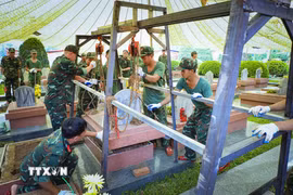 Phần nắp mộ liệt sỹ được nâng lên bằng hệ thống pa lăng xích. Đây là một trong những sáng kiến trong quá trình khai quật lấy mẫu của cán bộ, chiến sỹ Bộ Chỉ huy Quân sự tỉnh Điện Biên. (Ảnh: Xuân Tư/TTXVN)