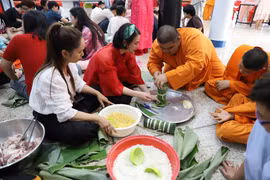 Các chú tiểu tại Chùa Phổ Phước rất quan tâm tìm hiểu văn hóa phong tục tập quán đón Tết của Việt Nam qua việc gói bánh chưng, bánh tét. (Ảnh: Đỗ Sinh/TTXVN)