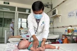 Bác sỹ khám cho bệnh nhi bị sốt xuất huyết. (Ảnh: Tuyết/TTXVN)