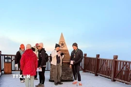 Du khách thích thú khi được trải nghiệm băng giá trên đỉnh Fansipan. (Ảnh: TTXVN phát)