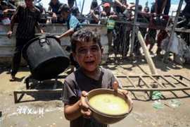 Em nhỏ Palestine nhận thức ăn cứu trợ tại thành phố Gaza, ngày 24/7/2025. (Ảnh: THX/TTXVN)